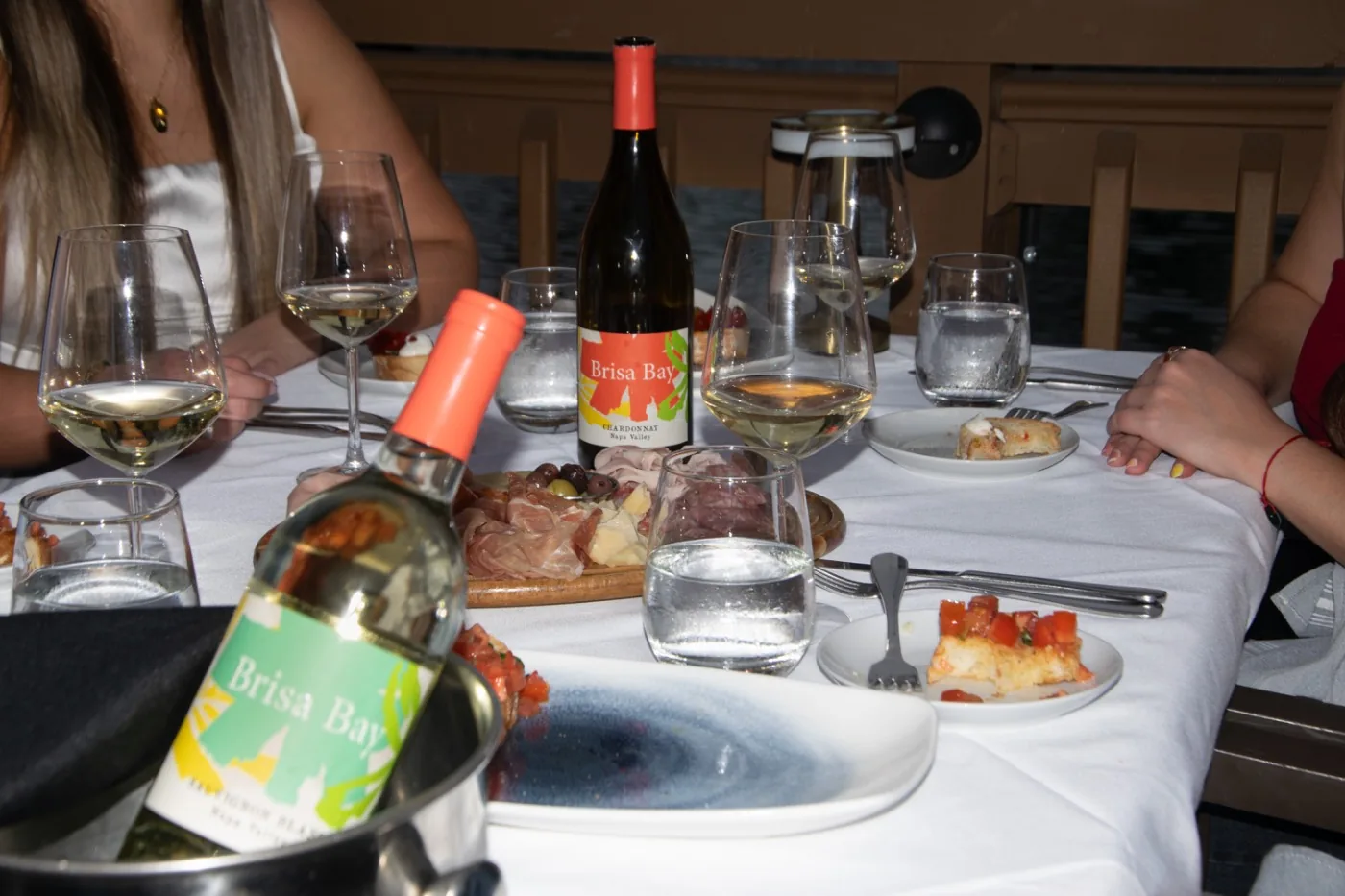 A table set with Brisa Bay bottles, white wine and small plates
